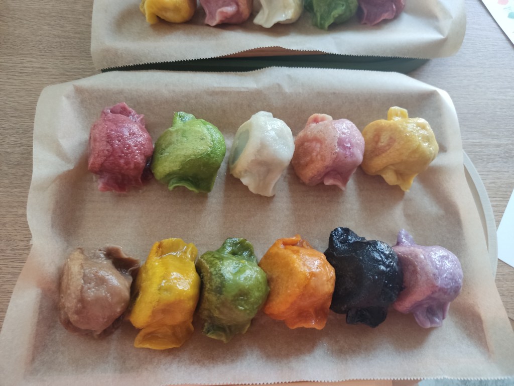 A plate with 11 gyoza, each one a different colour