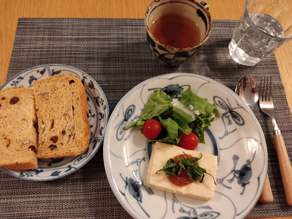 Two big slices of bread with fruit, a large piece of tofu with chutney and herbs, and a small salad
