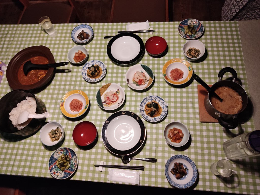 A table set for two, each person has seven small dishes of food. There are also pots of rice, curry, and soup for the diners to share.