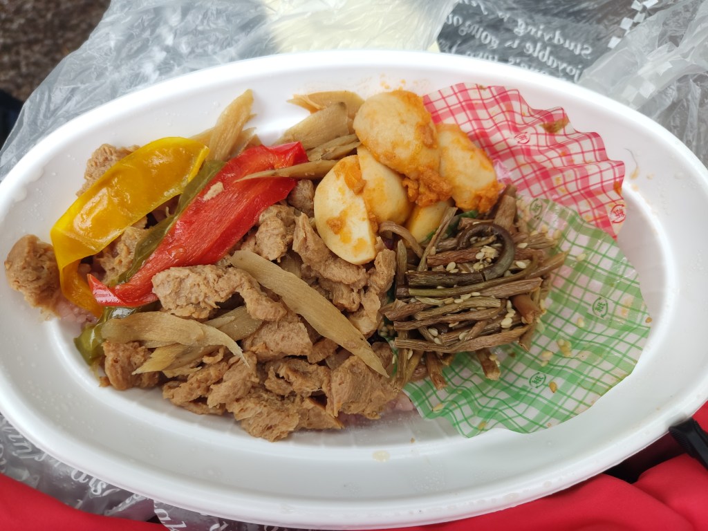 A disposable pot containing mock meat, potatoes, green beans, and peppers