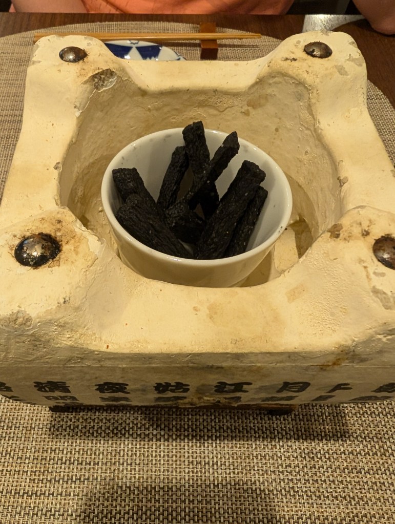 The heating device without the grill on top. Inside is a pot containing charcoal-black fries.