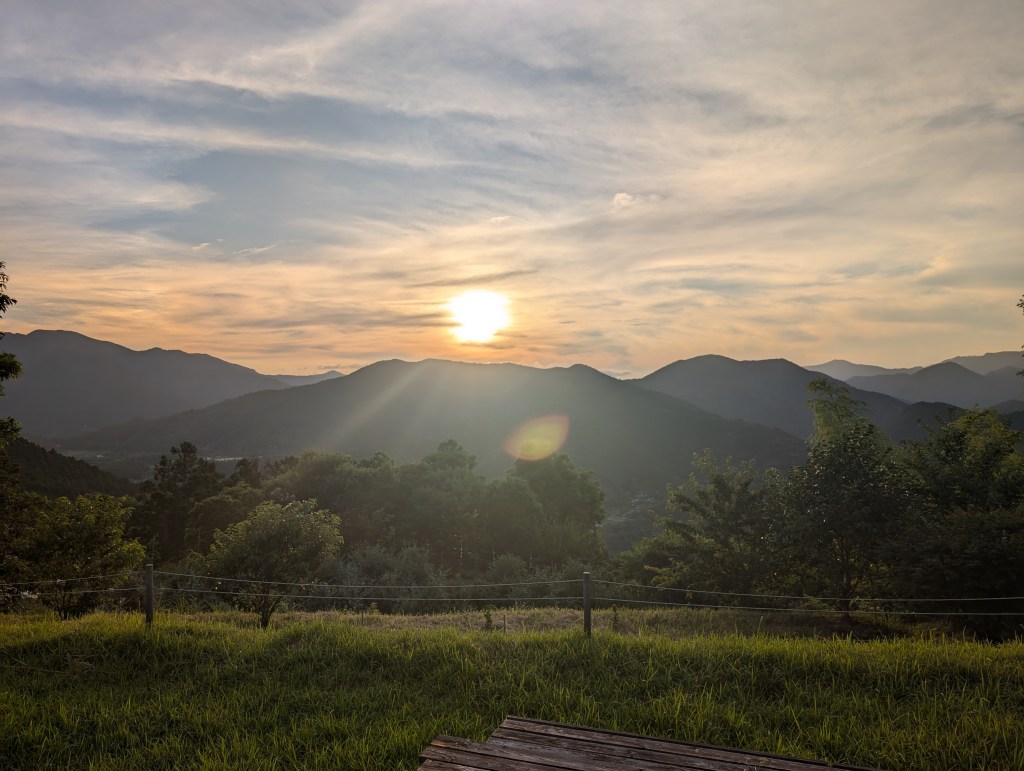 The sun setting behind green hills