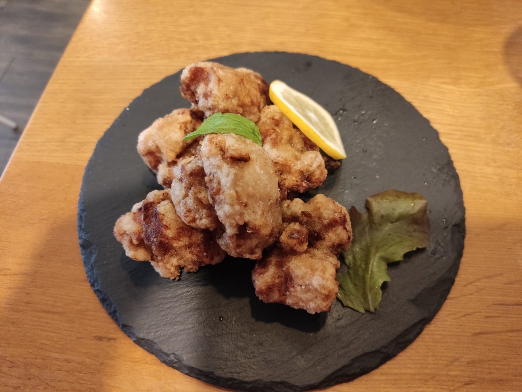 A black slate with several pieces of crispy looking fried vegan chicken