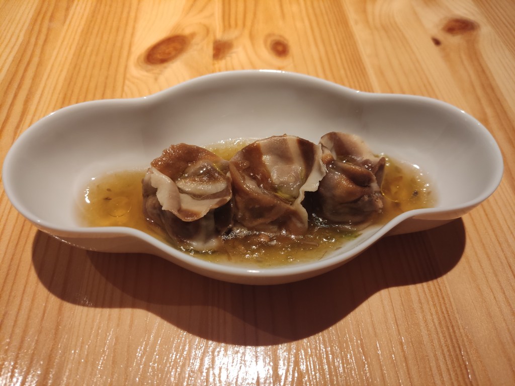 Three tortellini sitting in a clear brown broth