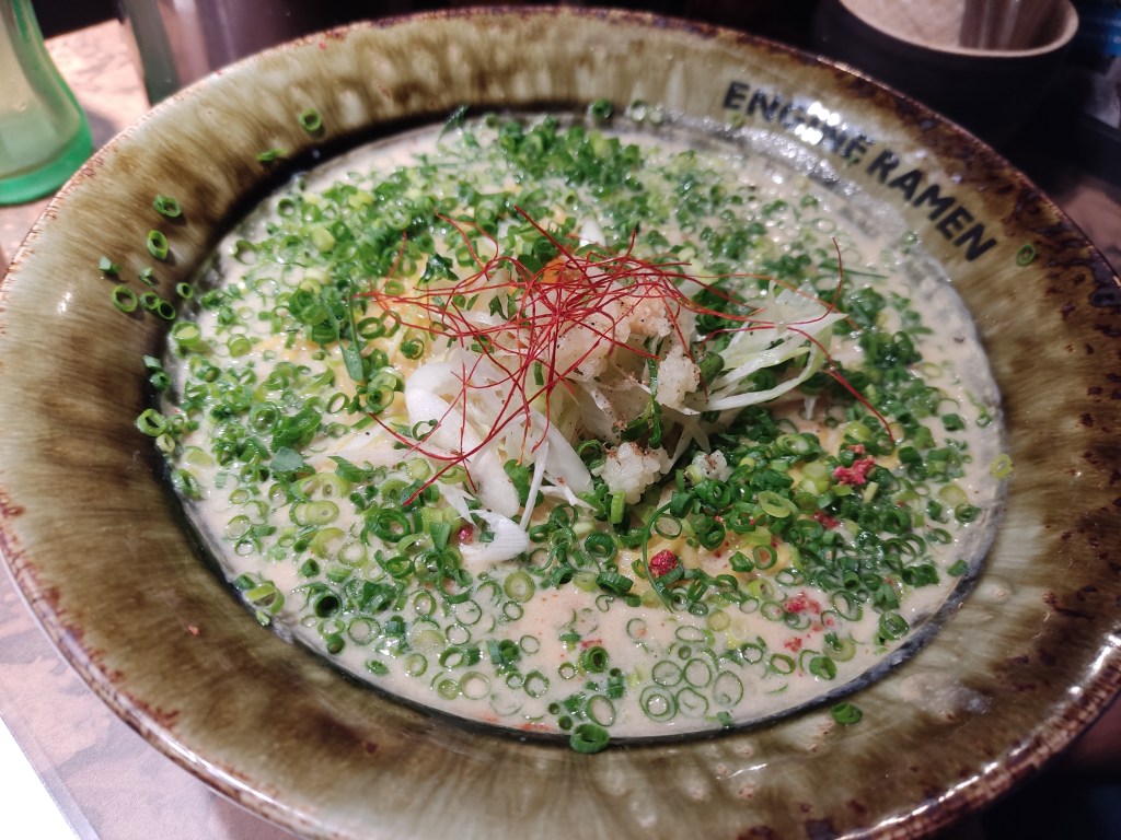 A bowl of creamy broth covered with spring onion