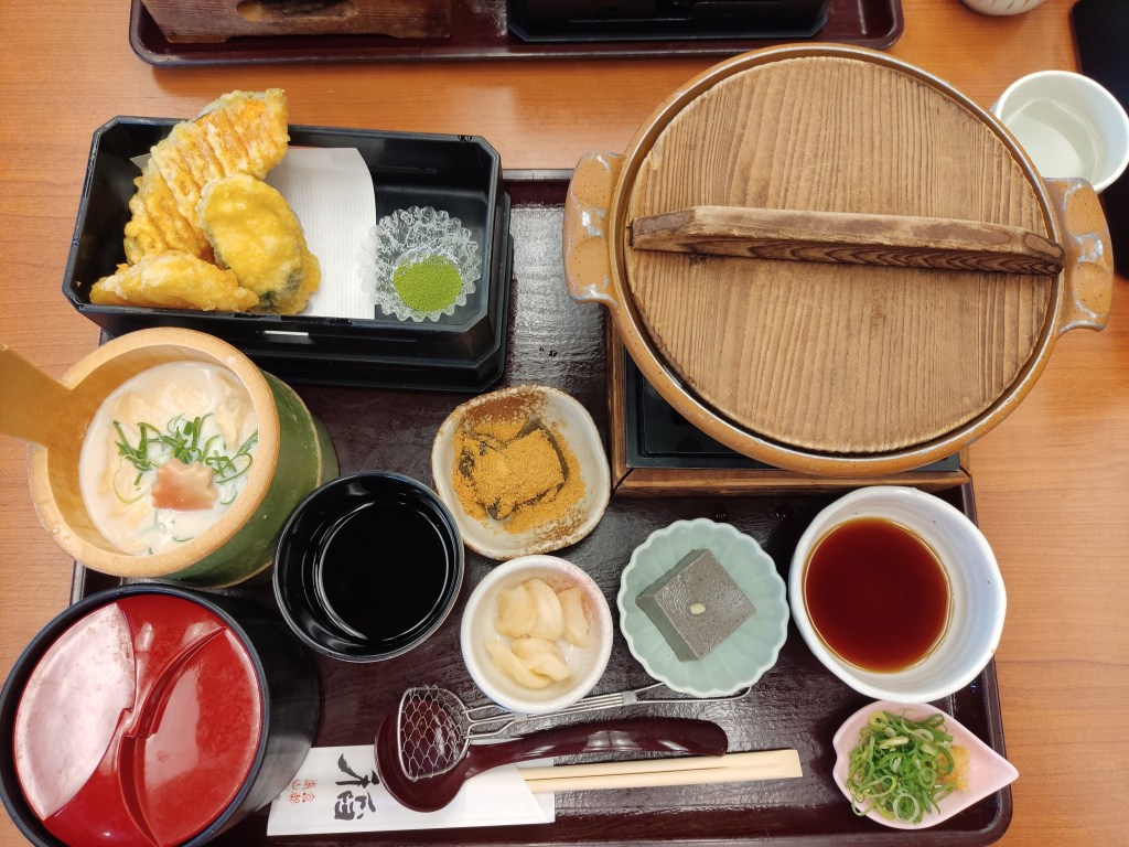 A tray containing lots of different dishes and utensils, most of the dishes are tofu prepared in different ways