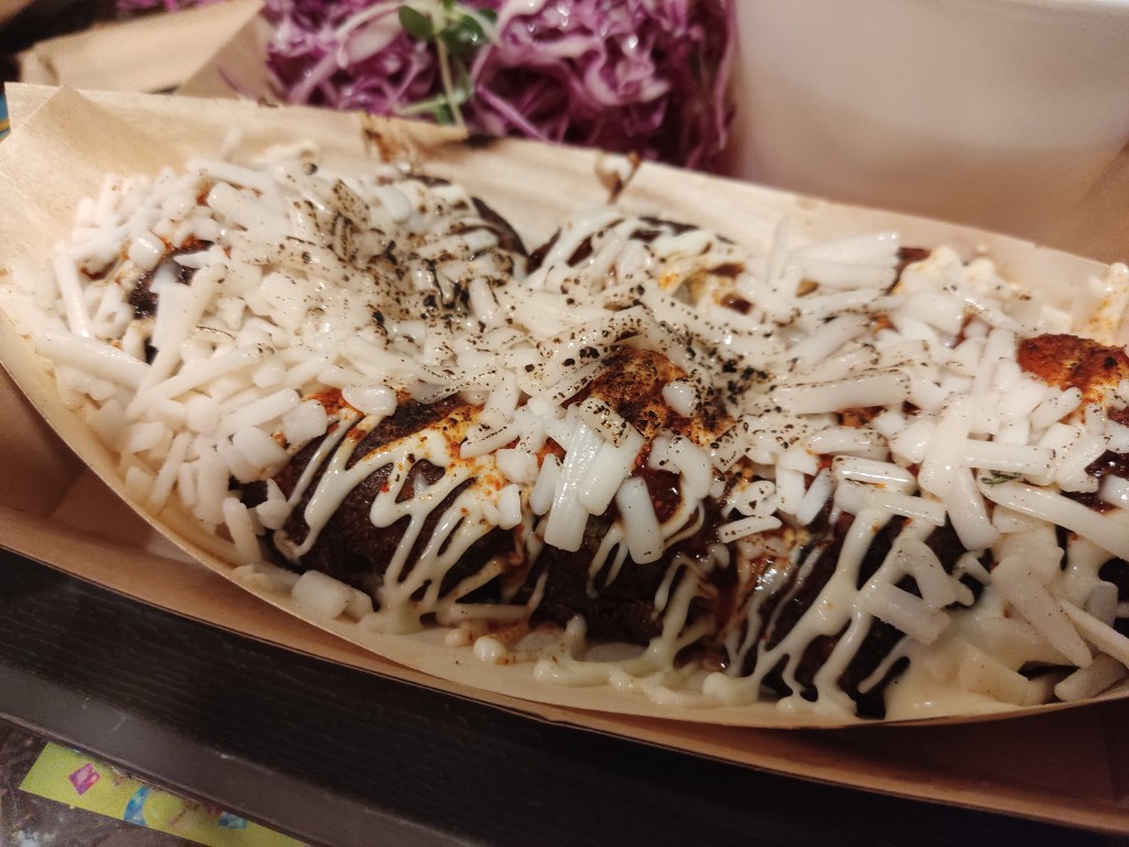 8 takoyaki balls drizzled with sauce and smothered with grated cheese