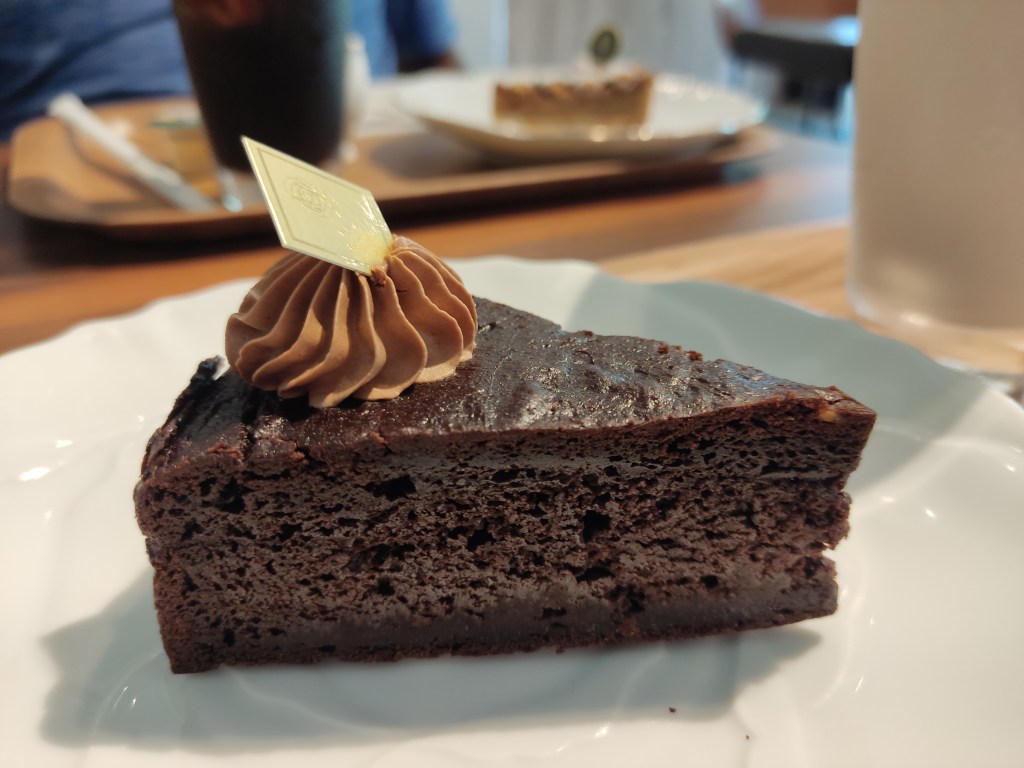 A slice of chocolate cake topped with chocolate cream