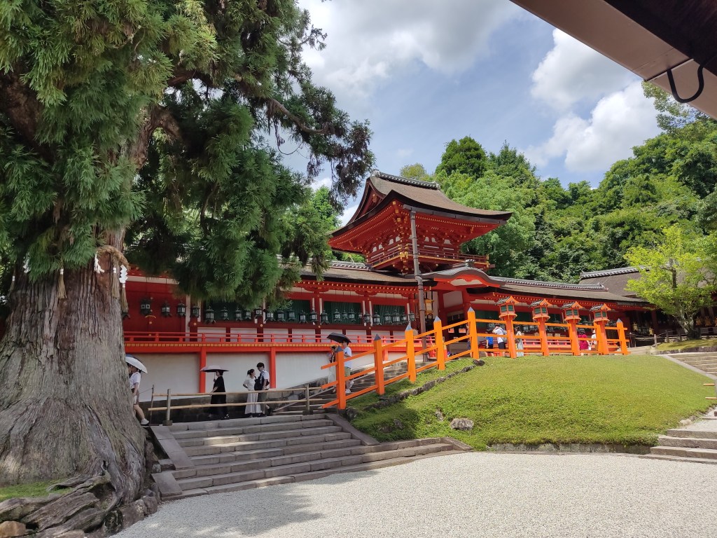 An orange and white shrine building surrounded by greenery