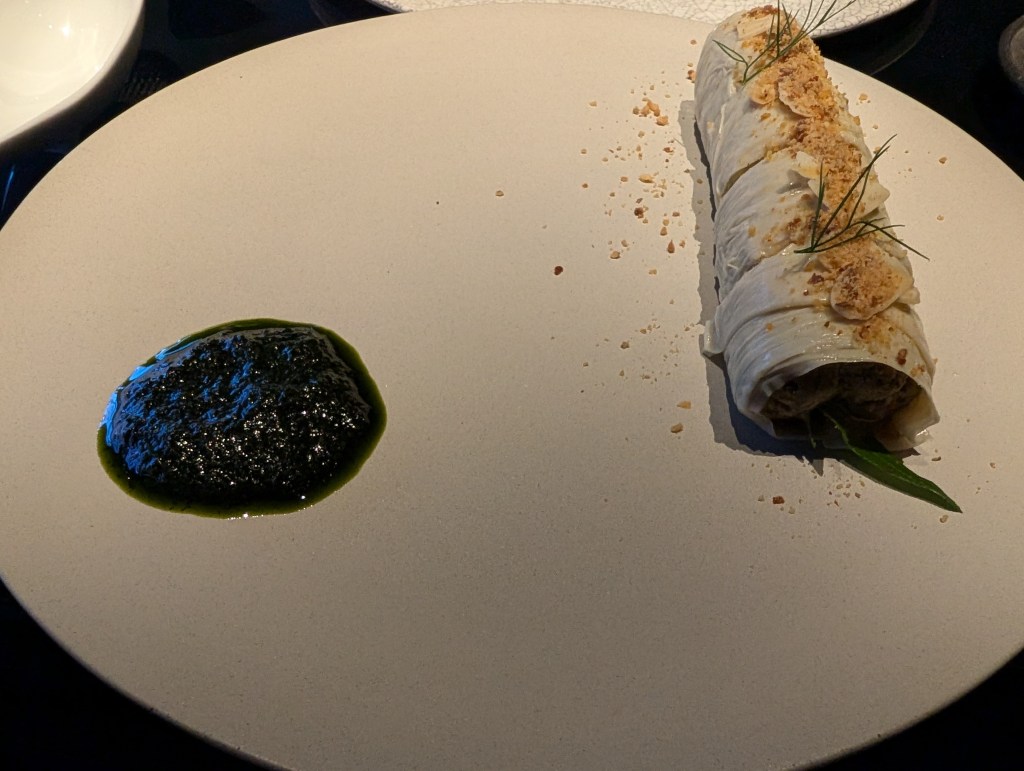 A line of yuba rolls and a dollop of dark green sauce