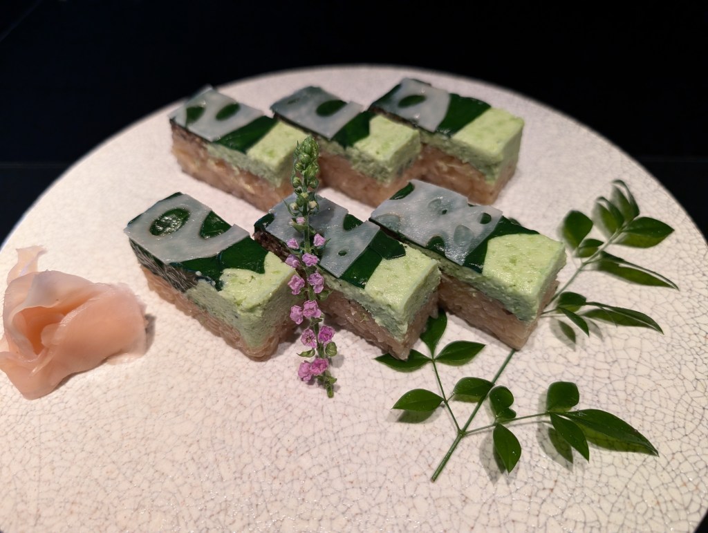 Six rectangular pieces of sushi topped with pale green wasabi