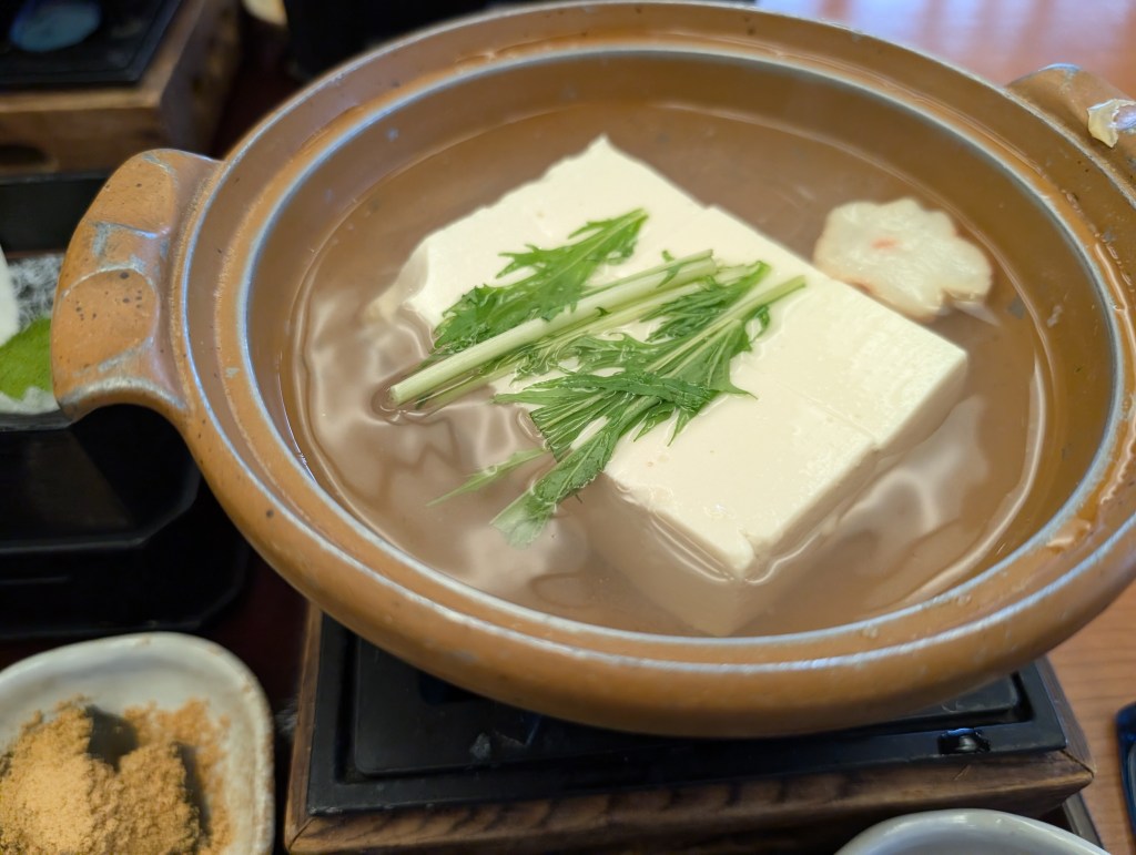 A pot filled with water in which a big block of tofu is cooking