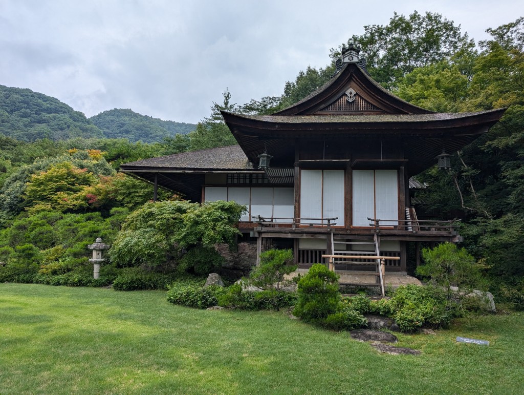 A traditional Japanese building surrounded by greenery on a well tended lawn