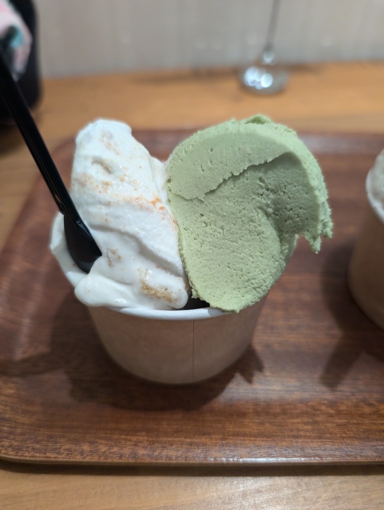 A cup with a scoop of white and a scoop of green ice cream