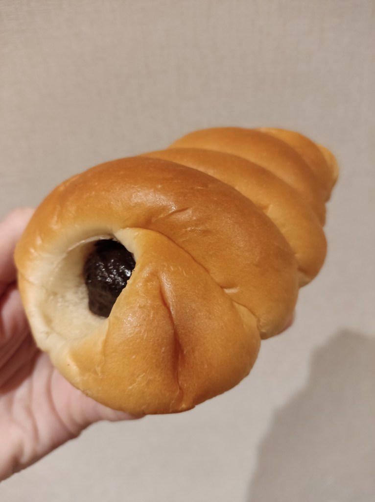 A long bun with chocolate poking out at one end