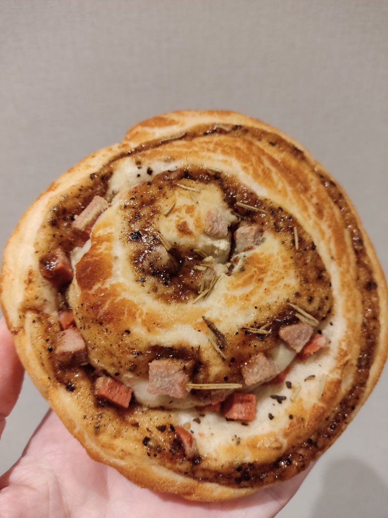 A bread snail with pieces of ham and sprigs of rosemary