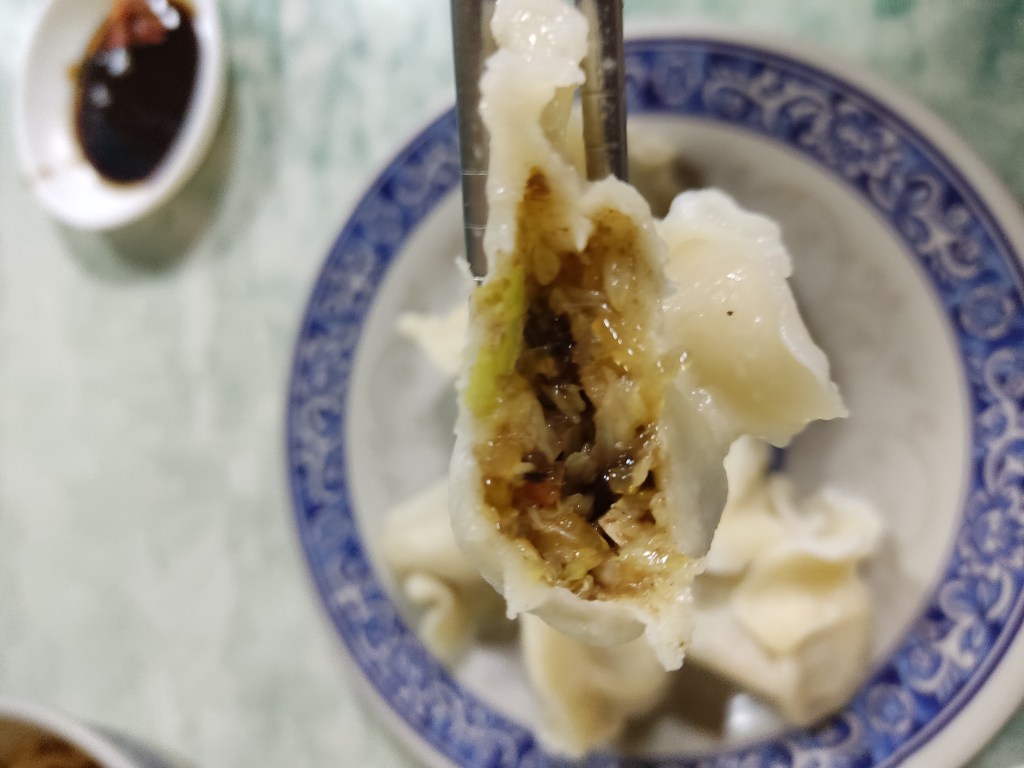The inside of a dumpling, showing the thinness of the wrapper and the cabbage filling