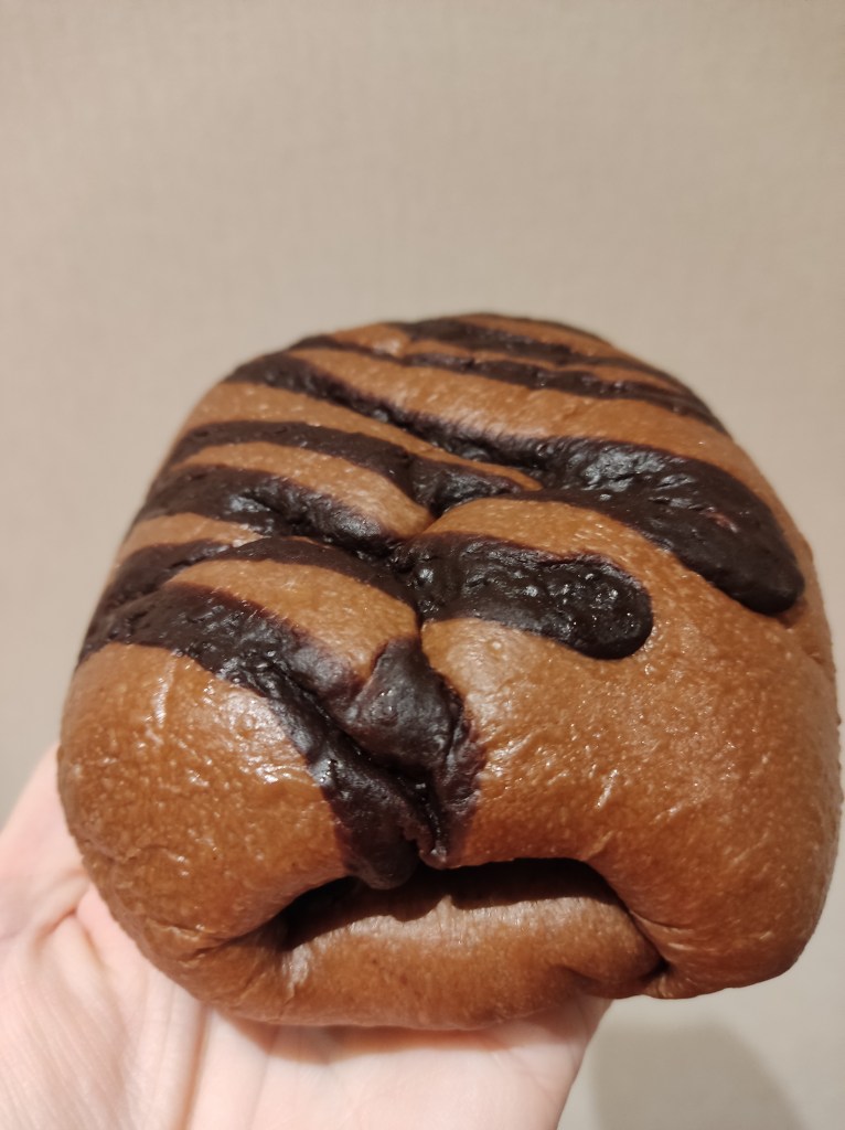 A large flat brown bun with chocolate stripes