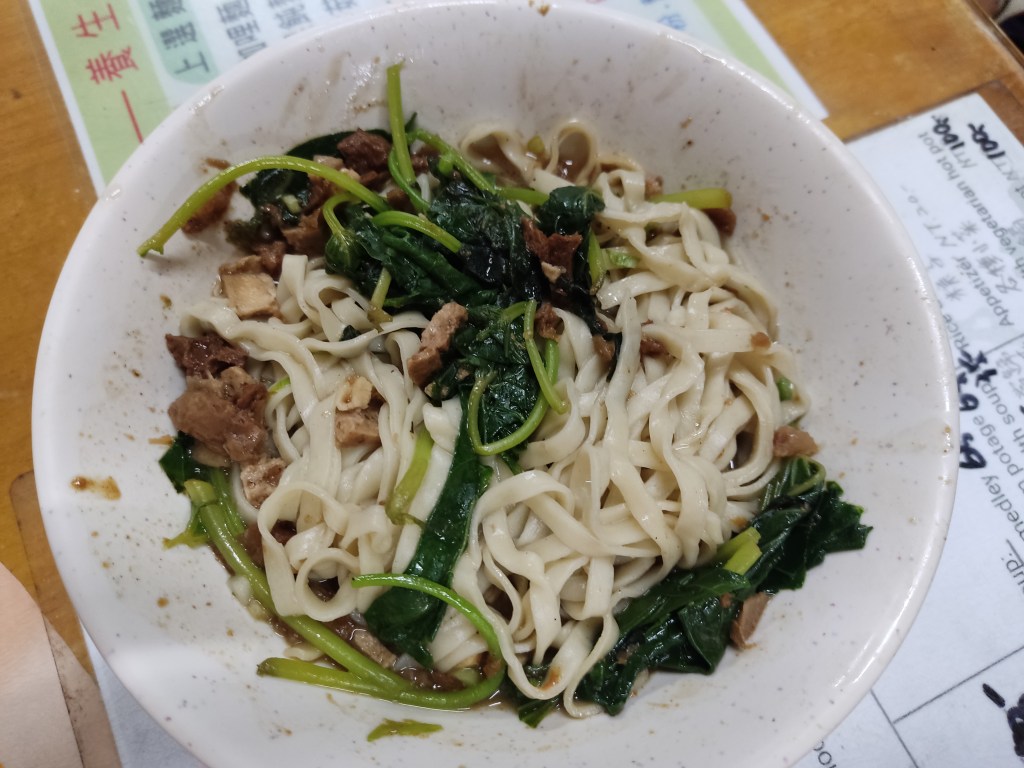 A big dish of flat noodles with greens and mock meat