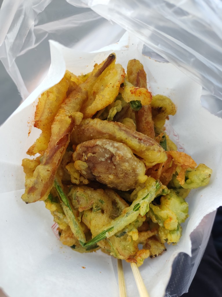 A bag of battered and fried vegetables and mushrooms dusted with orange powder