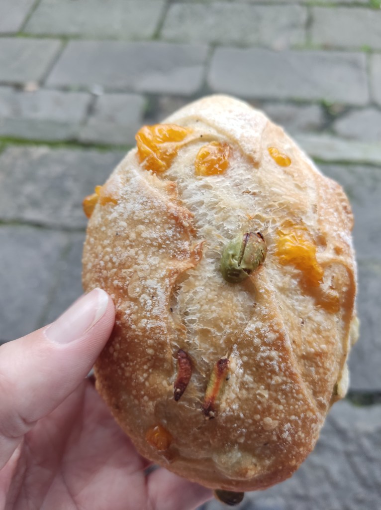 A bread bun with edamame beans and pockets of cheese on top