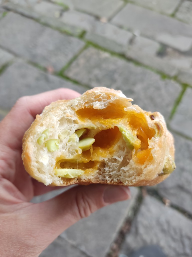 Inside of a bread bun with melted cheese and edamame