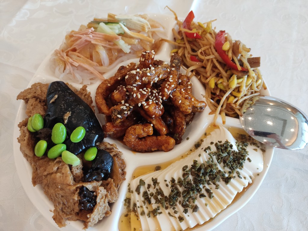 A platter with five components each containing a different dish