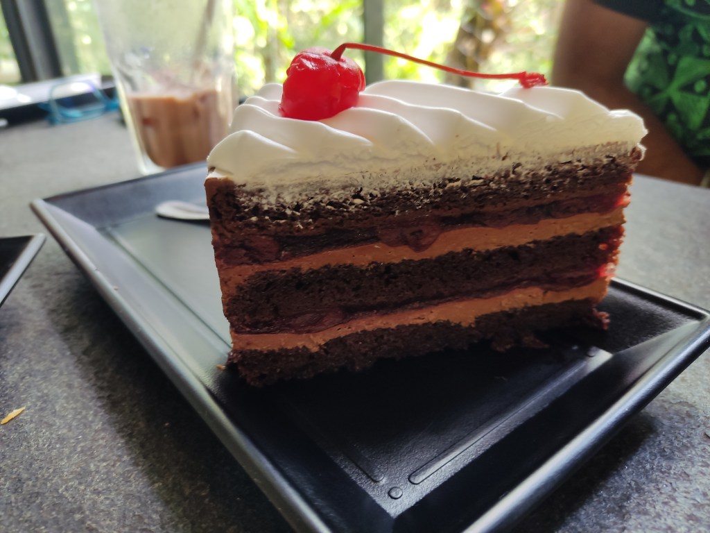 A slice of black forest cake topped with a cherry