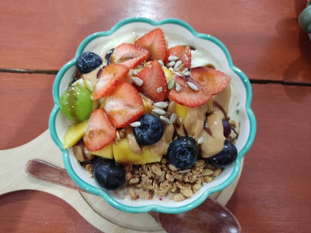 A bowl topped with granola, fruit, and peanut butter