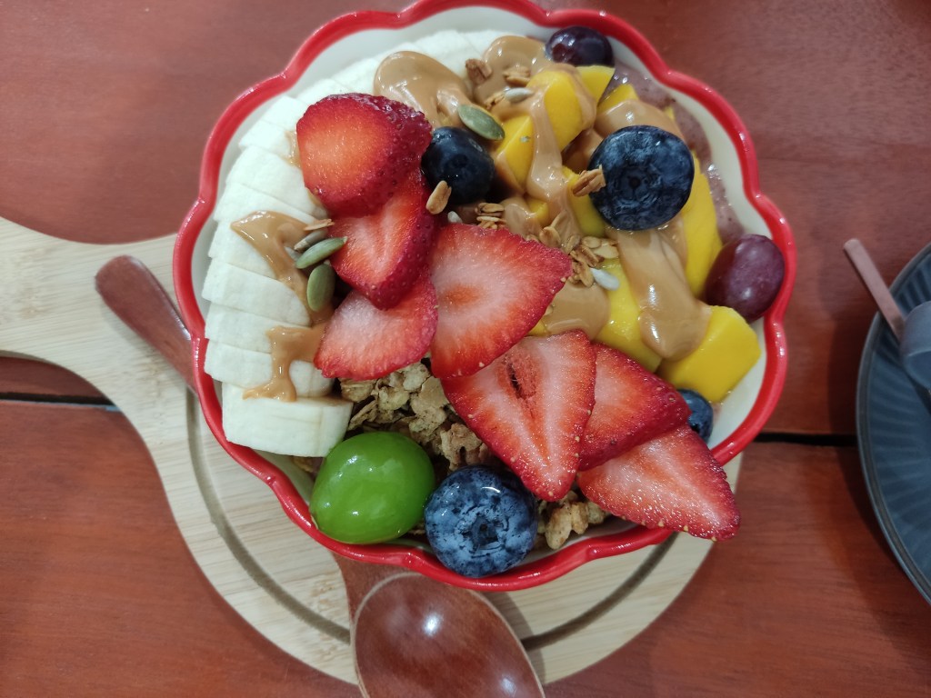 A bowl topped with granola, fruit, and peanut butter