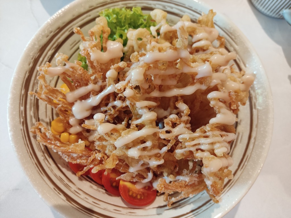 A bowl with mushroom tempura drizzled with mayo