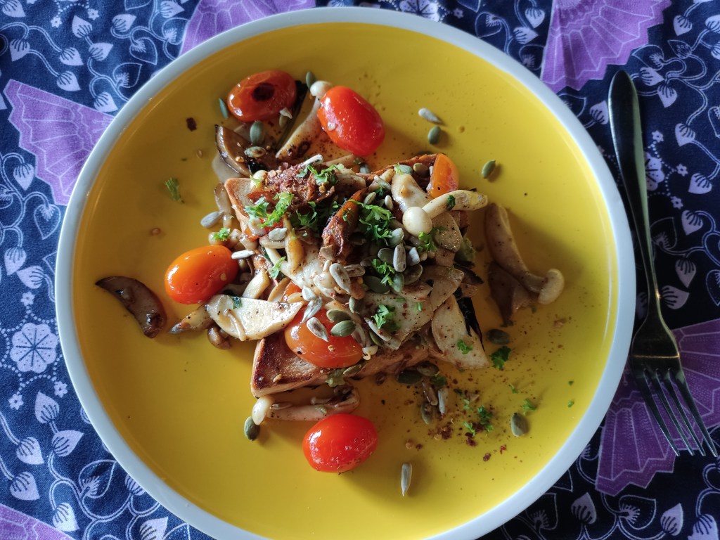 A large slab of toast topped with mushrooms and tomato