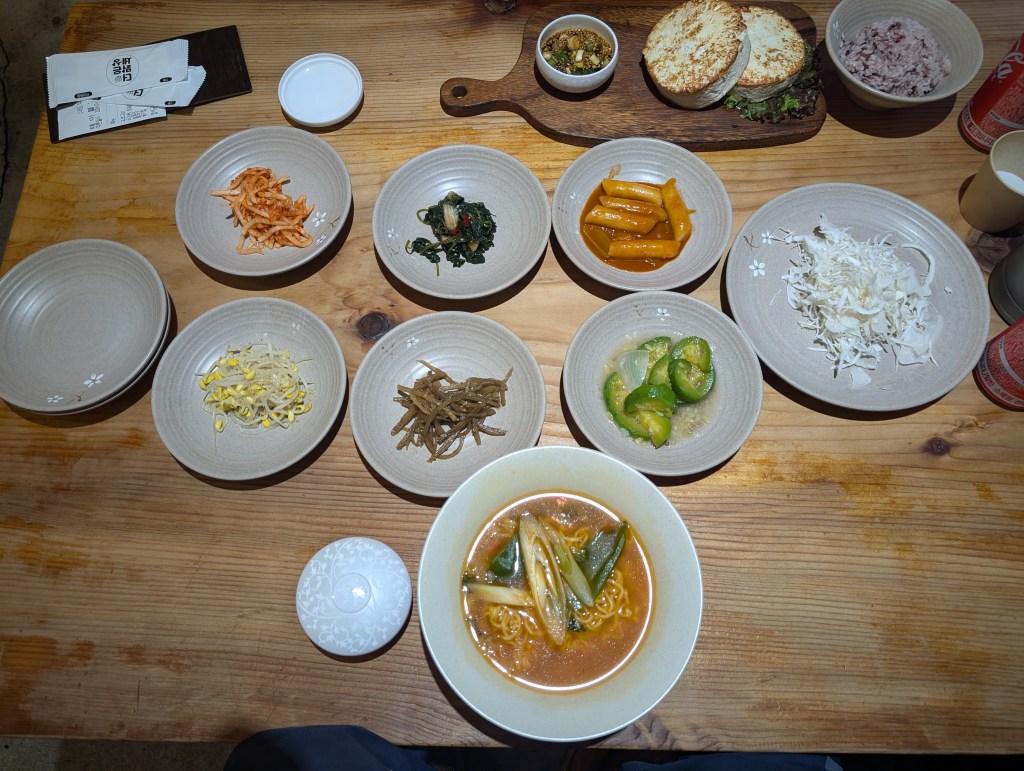 Ramen and tofu with seven plates of banchan in the middle of the table