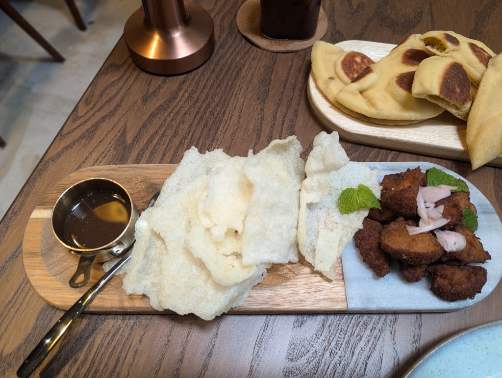Fried mushrooms alonside rice crackers and a pot of sauce