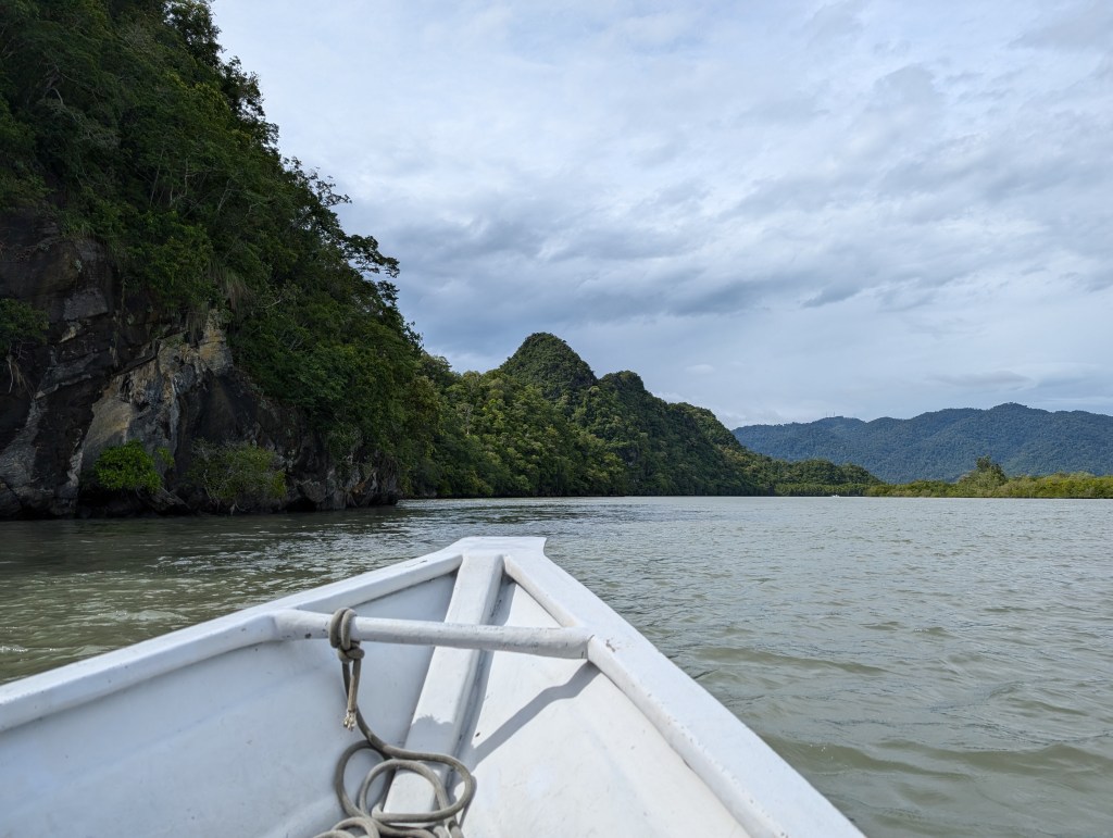 A small boat sailing alongside rocky cliffs