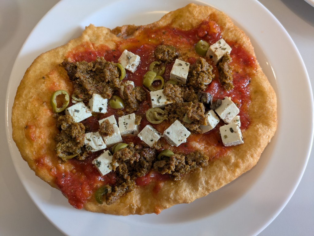 A big fried dough topped with tomato sauce, cheese, and olives
