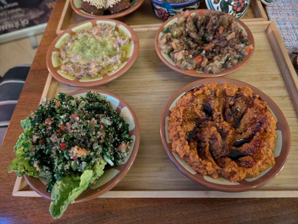 A tray with four dishes of food: foul, baba ganoush, walnut dip, and tabbouleh