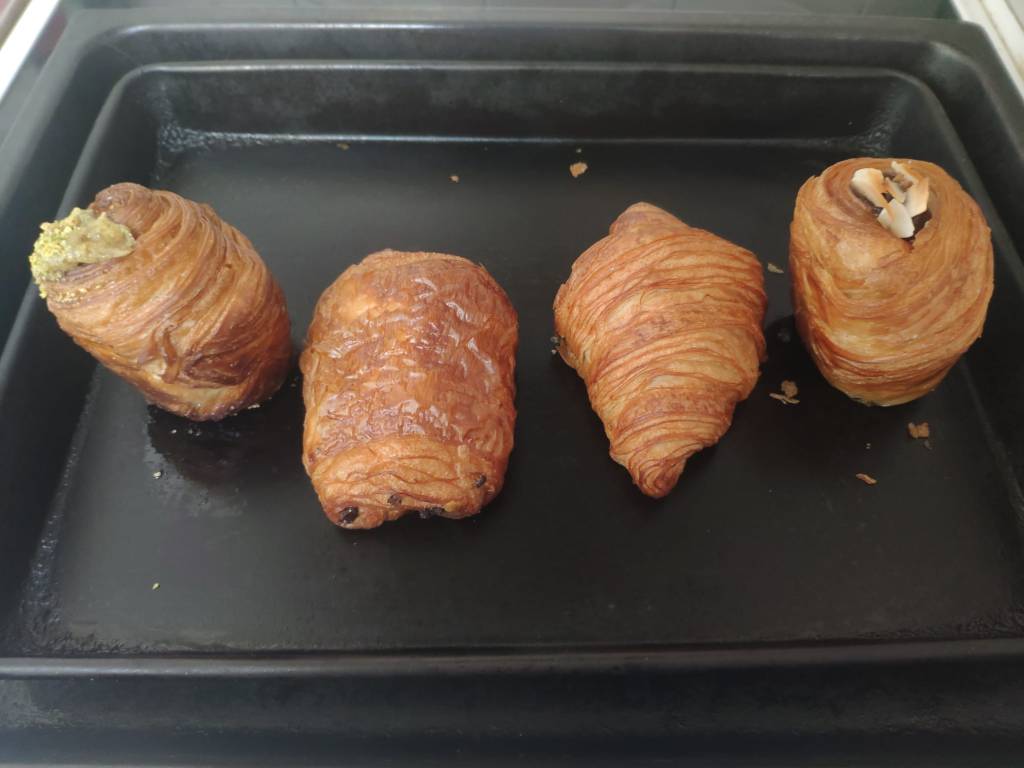 A baking tray ready for the oven with two krafins, a pain au chocolat, and a croissant