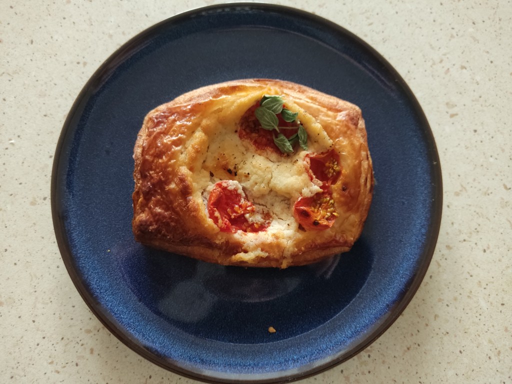 A small rectangular Danish pastry filled with cheese, tomato, and basil