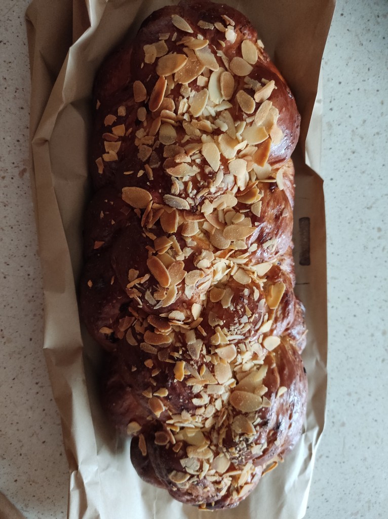 A plaited loaf of bread topped with slivered almonds