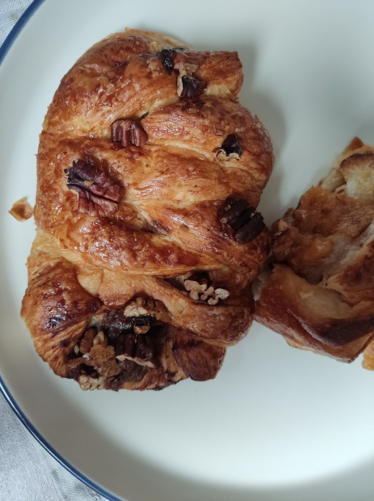 A plaited pastry topped with pecan chunks 