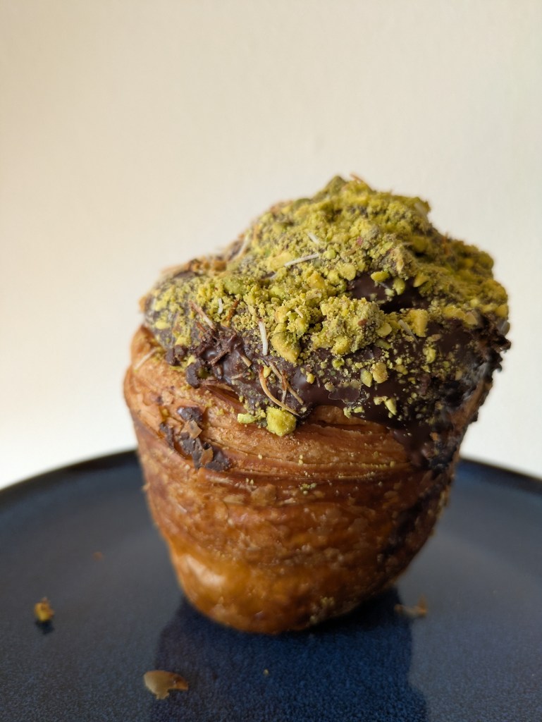 A Dubai krafin topped with thick chocolate and chopped pistachios 