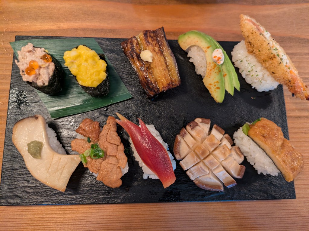 A slate with ten pieces of sushi on it, each one different 