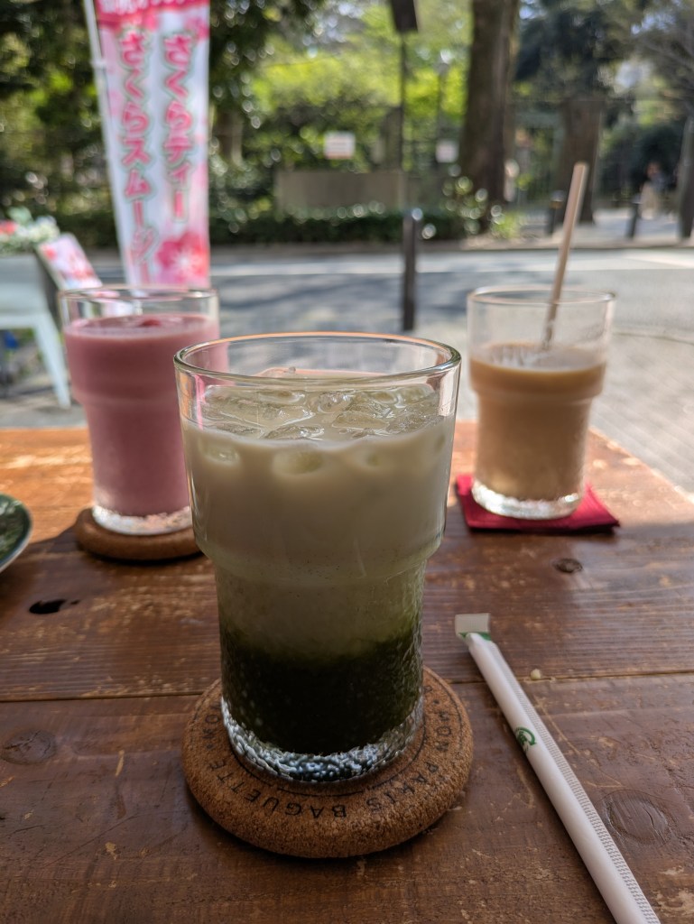 An iced matcha latte in the foreground with a pink smoothie and latte in the background 