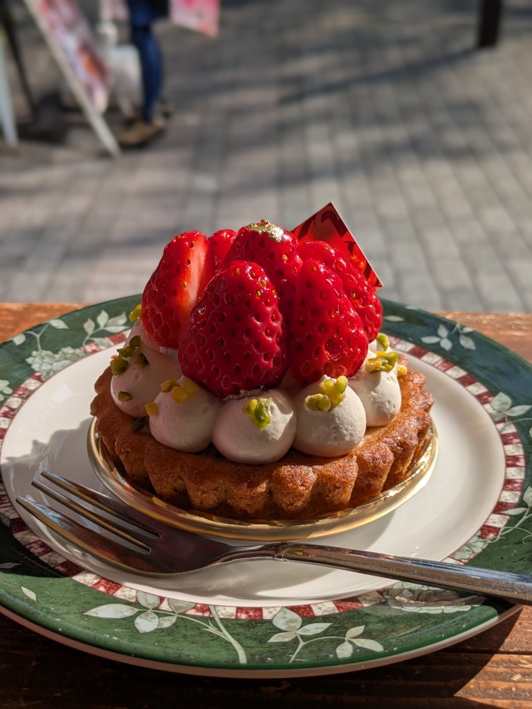 An individual tart topped with cream and strawberries