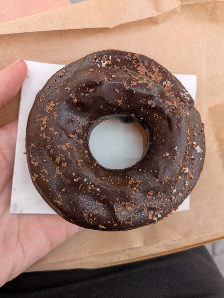 A ring donut with thick chocolate on top and a sprinkling of salt