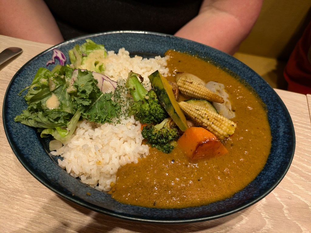 A bowl of side salad, rice, and curry sauce with vegetables
