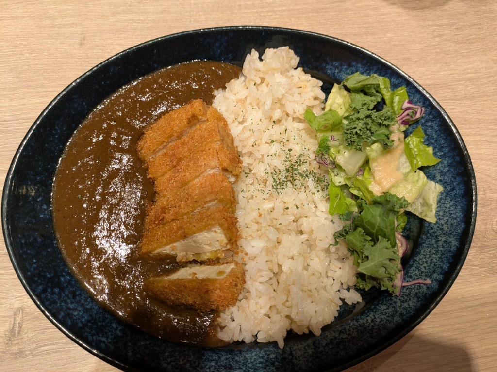 A bowl of side salad, rice, and curry sauce with katsu tofu