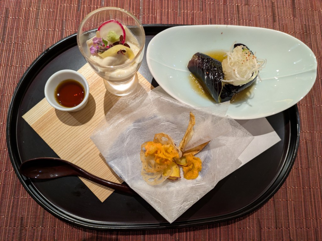A small glass of yuba in soy milk, some chunks of aubergine, and a few vegetable crackers