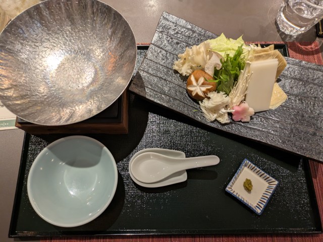 A tray with a hot pot cooking station alongside a plate of food for cooking